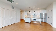Located at 1350 W Fifth Ave in Columbus, Ohio, this well-designed 2-bedroom, 2-bathroom residence offers a clean, modern aesthetic throughout its single-floor layout. The open-concept living area seamlessly integrates the kitchen, dining room, and living room, creating a bright and cohesive space anchored by warm light wood-tone flooring and crisp white walls.

The kitchen is a standout feature, showcasing white shaker cabinetry extending to the ceiling, a textured white tile backsplash, stainless steel appliances, and a central island with a quartz-style countertop illuminated by a pair of sleek black pendant lights. A dedicated pantry provides additional storage.

Both bedrooms are generously sized, filled with natural light from large windows, and finished with the same warm hardwood-style flooring. The primary bedroom offers a comfortable retreat with ample closet space. Each bathroom is thoughtfully appointed with white shaker vanities, grey countertops, subway tile surrounds, and matte black fixtures that add a contemporary contrast. One bathroom features a soaking tub, while the other offers a glass-enclosed shower.

Additional conveniences include in-unit laundry, four closets for abundant storage, and a private balcony. The consistent use of light tones, recessed lighting, and quality finishes throughout gives this residence a polished, move-in-ready appeal.