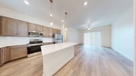 Located at 36635 W Honeycutt Rd in Maricopa, Arizona, this single-story, 3-bedroom, 4-bathroom home offers a clean, modern aesthetic with a thoughtfully designed open-concept layout. Light wood-look flooring flows throughout, complementing the bright, neutral palette that defines every room.

The kitchen serves as the heart of the home, featuring warm taupe cabinetry, a crisp white center island, stainless steel appliances including a range, microwave, and refrigerator, and stylish pendant lighting. It opens seamlessly into the living area, which benefits from natural light through large sliding glass doors dressed with vertical blinds and a ceiling fan overhead.

Each of the three bedrooms is well-proportioned, finished with the same wood-look flooring, ceiling fans, and window blinds that allow for ample natural light. Three dedicated closets provide organized storage, including a walk-in closet with built-in shelving accessible from one of the bathrooms. The bathrooms feature light wood vanities with white countertops, mirrors, and clean tub/shower combinations with chrome fixtures.

A dedicated laundry room houses a full-size side-by-side washer and dryer. The overall design is modern, low-maintenance, and move-in ready, making this Maricopa home a practical and inviting space.
