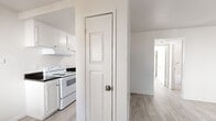 Located at 10780 Coloma Rd in Rancho Cordova, CA, this single-story 1-bedroom unit offers a clean, bright, and functional layout throughout. The living area is generously proportioned, featuring light wood-style laminate flooring, crisp white walls, and multiple windows dressed with patterned curtains that invite natural light. A ceiling fan and wall-mounted AC unit provide year-round comfort. The kitchen is efficiently designed with white cabinetry, dark speckled countertops, a double stainless steel sink, and a white electric range with overhead ventilation hood. Ample cabinet storage is present both above and below the counters. The bedroom is well-sized with large windows offering outdoor views of surrounding greenery, allowing for abundant natural light. A spacious walk-in closet with wrap-around shelving and a hanging rod provides excellent storage capacity. The bathroom features a vanity with warm-toned granite-style countertop, white cabinetry with under-sink storage, a large mirror with overhead lighting, and tile-style flooring. The unit's consistent light flooring and neutral white palette throughout create a cohesive, clean, and move-in ready environment.