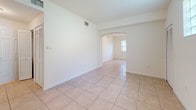Located at 677 NE 35 Ave, Unit 108 in Homestead, FL, this single-floor residence offers a well-organized layout with a clean, neutral aesthetic throughout. The living and dining areas feature light ceramic tile flooring and are connected by a graceful arched passageway, lending an open and airy feel to the common spaces. A distinctive glass block window allows natural light to filter into the entry area while maintaining privacy.

The kitchen is efficiently designed in a U-shaped galley configuration, outfitted with white cabinetry extending to the ceiling for ample storage, solid countertops, a textured tile backsplash, and white appliances including a refrigerator, range, and built-in microwave.

The bedrooms are carpeted for comfort and feature natural light from windows with blinds. Closet space is well-provided, with one bedroom offering a walk-in closet and another featuring a standard reach-in closet with wire shelving. A dedicated laundry area with washer and dryer hookups is conveniently accessible from the bedroom hallway.

The two bathrooms are finished in white tile with white vanities and mirrors. The full bath includes a soaking tub with shower combination, while the second bath provides a vanity with dual mirrors. The overall palette is bright and neutral, creating a clean, move-in-ready environment throughout.