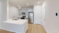 This well-appointed one-bedroom, one-bathroom unit at 2895 Easton Ave in Bethlehem, PA offers a thoughtfully designed single-floor layout with modern finishes throughout. The open-concept kitchen and living area forms the heart of the unit, where a sleek kitchen island with white quartz countertops and an undermount sink serves as both a functional workspace and a visual centerpiece. Elegant pendant lighting with a banded metallic design hangs above the island, complementing the gray shaker-style cabinetry and full suite of stainless steel appliances, including a refrigerator, range, and built-in microwave. Light wood-look flooring flows seamlessly throughout the entire unit, creating a warm and cohesive aesthetic. The living area is bright and airy, featuring a ceiling fan and a large sliding glass door with vertical blinds that invite natural light. The generously sized primary bedroom offers ample space, a dedicated closet, and a window with blinds. The bathroom is clean and functional, complete with a full tub-shower combination, a quartz vanity, and wood-look flooring. A dedicated closet with built-in shelving adds convenient storage. The unit's neutral color palette and modern finishes create a fresh, move-in-ready atmosphere.