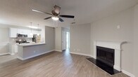Located in Dunwoody, GA, this single-floor residence offers a thoughtfully designed open-concept layout with consistent, neutral-toned finishes throughout. The living area is anchored by a classic white-mantled fireplace and is equipped with a ceiling fan, while wood-look flooring adds warmth and continuity. A sliding glass door invites natural light and provides access to an outdoor area. The kitchen is well-appointed with white shaker cabinetry, granite countertops, a subway tile backsplash, and a full suite of stainless steel appliances including a range, microwave, dishwasher, and refrigerator. A peninsula with pendant lighting and a built-in sink connects the kitchen seamlessly to the living space. A dedicated pantry or laundry closet is accessible directly from the kitchen. Both bedrooms feature plush carpeting, ceiling fans, and windows that bring in natural light. The two bathrooms mirror the kitchen's refined aesthetic, showcasing granite-top vanities with white cabinetry and framed mirrors. One bathroom includes a tub-shower combination with white tile surround. A textured ceiling is present throughout, adding subtle architectural character to the overall clean and modern interior design.
