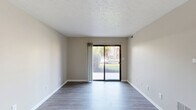 Located at 846 Harvest Dr in Kokomo, Indiana, this single-floor, two-bedroom, one-bathroom unit offers a well-organized and functional layout across a comfortably sized floor plan. The living room is bright and open, featuring smooth hardwood-style flooring, neutral warm-toned walls, a textured ceiling, and a large sliding glass door that fills the space with natural light and provides views of the surrounding outdoor greenery. The galley-style kitchen is well-appointed with white shaker cabinetry, granite-look countertops, stainless steel appliances including a refrigerator and microwave, and a double-basin sink — all set above light hardwood-style flooring. Both bedrooms are carpeted for comfort and feature neutral tones and natural light from windows with blinds. The primary bedroom includes a mirrored sliding closet with built-in shelving, while the second bedroom offers its own closet access through a hallway with dedicated shelving. The full bathroom is finished with a white vanity, quartz-style countertop, brushed nickel hardware, and hardwood-style flooring. Three hallways connect the rooms efficiently, and a dedicated closet provides additional storage. The unit's clean, neutral palette and practical layout make it a versatile and inviting space.