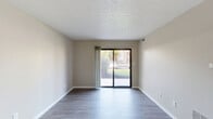 Located at 846 Harvest Dr in Kokomo, Indiana, this single-floor, two-bedroom, one-bathroom unit offers a well-organized and functional layout across a comfortably sized floor plan. The living room is bright and open, featuring smooth hardwood-style flooring, neutral warm-toned walls, a textured ceiling, and a large sliding glass door that fills the space with natural light and provides views of the surrounding outdoor greenery. The galley-style kitchen is well-appointed with white shaker cabinetry, granite-look countertops, stainless steel appliances including a refrigerator and microwave, and a double-basin sink — all set above light hardwood-style flooring. Both bedrooms are carpeted for comfort and feature neutral tones and natural light from windows with blinds. The primary bedroom includes a mirrored sliding closet with built-in shelving, while the second bedroom offers its own closet access through a hallway with dedicated shelving. The full bathroom is finished with a white vanity, quartz-style countertop, brushed nickel hardware, and hardwood-style flooring. Three hallways connect the rooms efficiently, and a dedicated closet provides additional storage. The unit's clean, neutral palette and practical layout make it a versatile and inviting space.