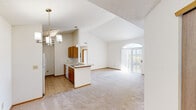Located at 1040 Windward Dr in London, Ohio, this single-floor, 2-bedroom, 2-bathroom home offers a well-designed layout with a bright, open feel. The living and dining area is anchored by striking vaulted ceilings that amplify the sense of space, with natural light streaming in through a large arched window and sliding glass door that leads to the outdoors. The kitchen features warm wood cabinetry, a peninsula with pendant lighting, tile flooring, and white appliances including a refrigerator and dishwasher. The open sightlines between the kitchen and living area create a cohesive, functional common space. Both bedrooms are carpeted and filled with natural light from generously sized windows. The primary bedroom offers a comfortable footprint with direct access to a closet. The second bedroom includes a ceiling fan with light fixture. Each bathroom is equipped with a full bathtub and shower combination, tile flooring, and clean white fixtures. A dedicated laundry room houses the in-unit washer and dryer with overhead wire shelving for additional storage. Two closets provide practical storage throughout the home. Neutral tones and textured ceilings are consistent throughout, lending the space a clean, move-in ready character.