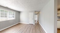 Located at 1351 Avondale Dr in Clarksville, Tennessee, this single-story, three-bedroom, one-bathroom home offers a practical and well-organized layout. The interior features a consistent gray color palette with crisp white trim throughout, creating a clean, neutral aesthetic.

The kitchen is equipped with white shaker-style cabinetry, light stone-look countertops, a double-basin sink, and white appliances including a range and dishwasher. Wood-look luxury vinyl plank flooring runs through the main living and kitchen areas, lending a warm, durable finish.

A central hallway connects the bedrooms, all of which feature soft carpeting and individual windows that invite natural light. The primary bedroom includes a double-door closet, providing ample storage. The additional bedrooms are similarly sized and well-lit, each with windows overlooking the exterior.

The bathroom features a tub/shower combination clad in white subway tile, maintaining the home's clean, consistent design language. Textured ceilings are found throughout the home. The dining or flex area adjacent to the kitchen offers wood-look flooring and direct access to an exterior door. Overall, the home presents a tidy, move-in-ready space suited for comfortable single-floor living.