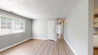 Located at 1351 Avondale Dr in Clarksville, Tennessee, this single-story, three-bedroom, one-bathroom home offers a practical and well-organized layout. The interior features a consistent gray color palette with crisp white trim throughout, creating a clean, neutral aesthetic.

The kitchen is equipped with white shaker-style cabinetry, light stone-look countertops, a double-basin sink, and white appliances including a range and dishwasher. Wood-look luxury vinyl plank flooring runs through the main living and kitchen areas, lending a warm, durable finish.

A central hallway connects the bedrooms, all of which feature soft carpeting and individual windows that invite natural light. The primary bedroom includes a double-door closet, providing ample storage. The additional bedrooms are similarly sized and well-lit, each with windows overlooking the exterior.

The bathroom features a tub/shower combination clad in white subway tile, maintaining the home's clean, consistent design language. Textured ceilings are found throughout the home. The dining or flex area adjacent to the kitchen offers wood-look flooring and direct access to an exterior door. Overall, the home presents a tidy, move-in-ready space suited for comfortable single-floor living.