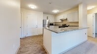 Located at 2000 NE Coronado Dr in Blue Springs, MO, this 2-bedroom, 1-bathroom unit offers a well-designed, single-floor layout. The kitchen is a standout feature, showcasing white shaker-style cabinetry, granite countertops, and a full suite of stainless steel appliances including a refrigerator, electric range, dishwasher, and built-in microwave. A peninsula with bar-style seating connects the kitchen to the open-concept living area, which is carpeted and brightened by a set of French-style doors that invite natural light. The two bedrooms are carpeted and finished with neutral tones, offering a calm and versatile environment. The primary bedroom includes a double-door closet, providing ample storage. The bathroom features a walk-in shower with a clean white surround, white cabinetry, and granite countertops consistent with the rest of the unit. A dedicated laundry room houses a full-size washer and dryer with overhead shelving for added utility. Wood-style vinyl flooring flows through the kitchen, bathroom, and laundry areas, complementing the warm, neutral color palette found throughout the entire space.