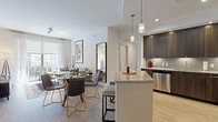 This single-floor residence showcases a thoughtfully designed interior with a contemporary aesthetic carried consistently throughout. The kitchen is a standout feature, outfitted with rich dark-wood cabinetry, light granite countertops, a neutral tile backsplash, and a full suite of stainless steel appliances including a range, built-in microwave, and dishwasher. Light wood-style flooring anchors the space and continues into the adjoining hallways, lending warmth and visual continuity.

Multiple bedrooms are present, each finished with the same light flooring, crisp white walls, and ceiling fans that contribute to a bright, airy atmosphere. Natural light filters in through windows dressed with sheer curtains, creating a soft and inviting ambiance. Several bedrooms include access to walk-in closets or adjoining spaces, adding functional appeal.

The bathrooms are finished with large-format marble-style porcelain tile, maintaining a clean, upscale look. One bathroom features a frameless glass walk-in shower with marble-surround walls and a built-in teak bench, while another offers a soaking tub with matching marble surround. Dark wood vanities with white countertops and chrome fixtures complete the refined look throughout.