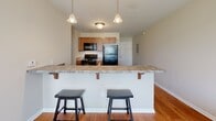 Located at 2333 Poshard Dr in Columbus, Indiana, this two-bedroom, two-bathroom unit offers a practical and well-organized single-floor layout. The kitchen is a functional highlight of the space, featuring warm wood cabinetry, granite-style countertops, and black appliances including a refrigerator, range, and microwave. A peninsula breakfast bar with pendant lighting above separates the kitchen from the living area, creating an open, connected feel. Hardwood-style flooring flows throughout the kitchen and main living areas, adding warmth and durability.

Each bedroom is carpeted for comfort and features a dedicated closet for storage. The primary bedroom includes a window that brings in natural light. Both bedrooms maintain a clean, neutral palette with beige walls that lend a calm, versatile atmosphere.

The two bathrooms each include a standalone shower stall with chrome fixtures, a toilet, and vanity cabinetry. The hardwood-style flooring continues into the bathrooms, providing a cohesive look throughout the unit.

Overall, this unit offers a straightforward, functional design suited for everyday living, with consistent finishes and a neutral color scheme that provides a solid foundation for personalization.