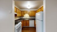 This single-floor, one-bedroom, one-bathroom unit is located at 278 Main St in West Haven, Connecticut. The layout is thoughtfully arranged, offering a comfortable and functional living environment throughout.

The kitchen is designed in a U-shaped configuration, maximizing efficiency and counter space. It features warm oak cabinetry with ample upper and lower storage, dark countertops, and wood-style flooring. White appliances are included, among them a gas range, dishwasher, and full-size refrigerator, along with an under-cabinet range hood and a stainless steel sink.

The open living area is generously sized, with neutral beige carpet covering the main lounge zone and wood-style flooring extending from the kitchen into the entry area. Soft, neutral wall tones and a window allowing natural light into the space contribute to a bright, welcoming atmosphere.

The bathroom is clean and functional, featuring a full-size tub and shower combination with a curved curtain rod, white fixtures, and wood-style flooring. Built-in shelving within the bathroom provides convenient storage.

Overall, this unit offers a practical and well-maintained living space in a straightforward, comfortable layout suitable for individuals or couples.