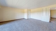 Located at 70 Lee Drive in Carnot, Pennsylvania, this single-floor residence offers a well-organized layout comprising three bedrooms, one bathroom, and a kitchen. The living area is generously proportioned, featuring plush wall-to-wall carpeting, a ceiling fan, and a large sliding glass door that floods the space with natural light and provides views of surrounding greenery. Warm, neutral-toned walls and a clean paneled ceiling carry throughout the home, creating a consistent and cohesive aesthetic.

The kitchen is thoughtfully equipped with rich dark wood cabinetry, white appliances including a refrigerator and range, a sink, and light tile flooring — providing a functional workspace for everyday cooking. 

Each of the three carpeted bedrooms offers a calm, understated atmosphere. The primary bedroom is a comfortable size, featuring louvered bi-fold closet doors for ample storage. The additional bedrooms are similarly finished, with one enjoying a bright window overlooking outdoor trees, and another also featuring built-in closet storage.

The bathroom is finished with classic mosaic tile flooring in a brown-and-cream pattern, tiled shower walls surrounding a full bathtub, and a wood-toned vanity. This residence presents a clean, move-in ready environment with a straightforward, functional design throughout.