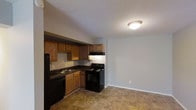 This single-floor 1-bedroom, 1-bathroom unit offers a practical and well-organized layout designed for comfortable everyday living. The kitchen is equipped with a full suite of black appliances, including a refrigerator, electric range with overhead exhaust, and dishwasher. Oak-toned cabinetry provides ample upper and lower storage, complemented by dark countertops and a stainless steel sink. The kitchen flows openly into the adjacent living area, creating a connected and functional common space. Tile flooring runs throughout the main area, offering durability and ease of maintenance. A textured ceiling adds a classic finish to the interior, while flush-mount ceiling lighting provides consistent illumination. Neutral-toned walls throughout keep the space feeling clean and adaptable to a variety of décor styles. The open transition between the kitchen and living space allows for flexible furniture arrangement and maximizes the sense of openness within the unit. Overall, the space is thoughtfully designed to balance functionality and comfort within a compact, efficient footprint.