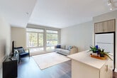 Located at 222 M Street Southwest in Washington, DC, this well-appointed one-bedroom, one-bathroom residence offers a thoughtfully designed floor plan that maximizes functionality and comfort. The open-concept kitchen and living area serves as the heart of the home, featuring warm wood-tone cabinetry, light quartz countertops, a center island, and white appliances including a refrigerator, electric range, microwave, and dishwasher. Track lighting illuminates the kitchen, while wood-look flooring runs throughout the main living spaces. The living room is bright and airy, benefiting from oversized windows that frame views of a lush courtyard, flooding the space with natural light. The private bedroom offers plush carpeting, neutral tones, and a sliding-door closet for ample storage. The full bathroom features large-format white tile flooring, a combined tub and shower, and a modern vanity with clean, minimalist finishes. A dedicated laundry room with a stacked washer and dryer adds exceptional convenience. Throughout the residence, a cohesive neutral palette and contemporary design create a calm, functional living environment in the heart of Southwest Washington, DC.