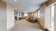 Located at 205 Church Street in the heart of downtown New Haven, CT, this single-floor space offers a thoughtfully designed layout across two living areas, a hallway, and a full bathroom. The interior is finished with neutral warm and gray tones, plush carpeted flooring throughout, and recessed lighting that provides consistent, even illumination across all rooms.

The primary living area is generously proportioned, featuring multiple windows with slatted blinds that allow for controlled natural light and views of the surrounding urban environment. This room is well-suited for lounging or informal gatherings, with an open, welcoming ambiance. A secondary living area serves a more functional, professional purpose — equipped with a built-in counter workspace, swivel chairs, a large conference table, wall-mounted display, and framed artwork, making it ideal for meetings or collaborative work sessions.

The hallway connects the two main areas seamlessly, incorporating a vanity with mirror and sink. The bathroom is fully ADA-compliant, featuring stainless steel grab bars, a pedestal sink, and clean tile flooring, ensuring accessibility for all users. Throughout the space, the design balances comfort and functionality, creating a versatile environment suited for both professional and community-oriented purposes.