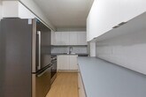 Located at 1333 Ouellette Ave in Windsor, Ontario, this well-appointed two-bedroom, two-bathroom unit offers a thoughtfully laid-out single-floor plan with a clean, modern aesthetic. Light hardwood flooring runs throughout the main living areas and bedrooms, complementing the neutral grey and white colour palette that gives the space a bright, airy feel.

The combined living and dining area is generously sized, featuring a large sliding glass door that opens onto a private balcony and fills the room with natural light and outdoor views of the surrounding neighbourhood. A baseboard heating unit ensures year-round comfort. The kitchen is conveniently accessible from the living area and features contemporary cabinetry and appliances.

A central hallway connects the bedrooms, bathrooms, and closets in an efficient layout. The primary bedroom is spacious and well-lit by a natural window, while the second bedroom offers comparable comfort and flexibility. Both bedrooms benefit from the consistent hardwood flooring and neutral wall tones found throughout the unit.

The two bathrooms are finished with light ceramic tile flooring, white fixtures, and grey countertops, presenting a clean and functional design. Two dedicated closets provide practical storage. Wall sconces and flush-mount ceiling fixtures contribute to consistent, well-distributed lighting throughout the space.
