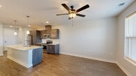 This single-floor unit offers a thoughtfully designed open-concept layout that seamlessly connects the kitchen and living areas. The kitchen is a standout feature, equipped with rich dark-toned shaker-style cabinetry, granite countertops, a classic white subway tile backsplash, and a full suite of stainless steel appliances including a refrigerator, electric range, and built-in microwave. A large center island with a granite top and undermount sink anchors the space, complemented by stylish pendant lighting overhead. Wood-look flooring flows throughout the main living areas, adding warmth and continuity.

The living and dining areas are bright and open, with a ceiling fan providing comfort and natural light filtering in through windows with blinds. Multiple bedrooms offer plush carpeting, ceiling fans, and generous natural light, creating comfortable and versatile spaces.

The unit includes two bathrooms, each finished with granite-topped dark wood vanities. One bathroom features a dedicated walk-in shower with chrome fixtures, while the other offers a full soaking tub and shower combination. Clean white walls and wood-look flooring carry through the bathrooms, maintaining a cohesive, contemporary aesthetic throughout the entire unit.