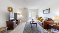 This single-floor residence in Toledo's University Hills neighborhood offers a thoughtfully arranged layout encompassing two bedrooms, two bathrooms, a living room, dining room, kitchen, and hallway. The carpeted living room serves as the heart of the home, featuring a textured ceiling and a sliding glass door that opens to a private balcony with outdoor views, filling the space with natural light. Adjacent to the living area, a compact dining nook provides an intimate setting for meals.

The kitchen features grey cabinetry, a double-basin sink, and black appliances, including a range and dishwasher, set atop wood-look flooring that adds warmth to the space. The primary bedroom is generously proportioned, offering carpet flooring, a window with natural light, and ample room for a full furniture arrangement. The second bedroom is similarly carpeted and well-lit. Both bathrooms are cleanly designed; one features an extended vanity with a wide mirror, and a separate tub/shower combination with built-in shelving. Throughout, neutral walls and light tones create a bright, cohesive ambiance.