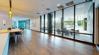 Located at 125 NE 32nd St in Miami's Upper Eastside neighborhood, this expansive single-floor amenity space offers a generously sized, thoughtfully designed communal environment ideal for socializing, lounging, and casual gatherings. The layout flows seamlessly from zone to zone, unified by warm wood-look tile flooring and crisp white walls throughout.

At the heart of the space is a sleek café-style bar counter with pendant lighting — a striking cascade of amber and tinted glass globes — paired with a built-in banquette and bar stools. Adjacent dining areas feature vibrant channeled banquette seating in tones of tan, sage, and emerald green, complemented by white bistro tables and mixed chairs. A large-scale cityscape mural adds artistic character to one dining nook.

The lounge area is anchored by generous sectional seating atop colorful area rugs, beneath modern circular pendant fixtures. A bold chevron-patterned accent wall in deep reds, purples, and magentas serves as a striking focal point. A billiards table adds a recreational element to the space.

Floor-to-ceiling glass curtain walls line the perimeter, flooding the interior with abundant natural light and offering unobstructed views of the lush outdoor terrace and surrounding landscape. The entry hallway features a curved glass facade, providing a bright, welcoming transition into the space.