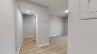 This single-floor unit in Hartford, CT presents a clean, modern aesthetic defined by neutral gray walls, crisp white trim, and light wood-tone luxury vinyl flooring throughout. The open layout is revealed clearly in the dollhouse view, showcasing a well-organized floor plan with distinct living, sleeping, and utility areas connected by a central hallway.

The kitchen is a standout feature, equipped with dark-stained shaker-style cabinetry paired with marble-look countertops and a coordinating subway tile backsplash. A stainless steel undermount sink and dishwasher complete the functional workspace, offering a polished, contemporary feel.

The bedrooms are bright and comfortable, each benefiting from natural light through double-pane windows fitted with blinds. One bedroom includes a closet with built-in shelving, while both rooms are served by baseboard heating and wall-mounted air conditioning units for year-round climate control.

The bathroom is elegantly appointed with full marble-patterned tile surrounding the soaking tub and shower, complemented by a rich dark wood vanity topped with a granite-look surface. The overall ambiance of the unit is clean, updated, and move-in ready.
