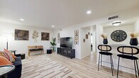 Located at 4503 Lake Ave in Dallas, TX, this well-designed 2-bedroom, 2-bathroom home delivers a cohesive modern aesthetic across a thoughtfully organized single-floor layout. The living room is a bright, inviting space featuring light wood-look flooring, recessed lighting, and large windows dressed with sheer curtains that allow generous natural light to fill the room. Decorative wall art and a patterned area rug add warmth and character to the space. Adjacent to the living area, a bar-height counter with stylish seating connects seamlessly to the kitchen, which features a classic galley configuration with white cabinetry, granite-style countertops, black hardware accents, and light wood flooring. The dining area offers an intimate setting with natural light streaming through multiple windows. Both bedrooms are carpeted and offer a calm, comfortable retreat, with the primary bedroom featuring a ceiling fan and ample closet space. The bathrooms are clean and functional, with one featuring a tiled tub-shower combination. Three closets throughout provide excellent storage. The overall ambiance is bright, modern, and cohesive, with a neutral white palette and carefully chosen accents creating a stylish yet practical living environment.