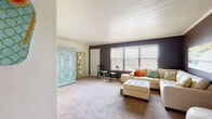 This single-floor residence offers a thoughtfully designed layout that balances comfort and functionality across its main living areas. The living room is a standout space, featuring bold charcoal-toned accent walls, soft wall-to-wall carpeting, and a large window fitted with horizontal blinds that allow generous natural light to filter in. The room comfortably accommodates a generous sectional sofa with a tufted ottoman, creating an inviting atmosphere for relaxation or entertaining.

The kitchen is efficiently designed with rich, dark wood cabinetry, granite-toned countertops, a double-basin sink, a dishwasher, and a coil-top electric range. Stone-tile flooring adds durability and visual warmth to the space.

The two bedrooms are carpeted and well-sized, each offering closet storage. The primary bedroom features a set of double panel closet doors and a window that brings in natural light. The second bedroom also includes a window and ample floor space.

Both bathrooms are finished with the same stone-tile flooring seen in the kitchen, dark wood vanities, and granite-toned countertops. One bathroom includes a shower-tub combination, while the other also offers a tub with shower. The overall ambiance of the residence is cohesive, combining warm tones with tasteful contrasts for a comfortable and functional living environment.
