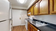 Located at 3214 Hewitt Ave in Silver Spring, this 2-bedroom, 1-bathroom residence offers a practical and comfortable single-floor layout. The kitchen is outfitted with warm oak cabinetry, dark granite-style countertops, a gas range, dishwasher, and a stainless steel sink — all set atop durable hardwood-style flooring. A hallway connects the main living spaces, leading to a generously sized living area with plush carpeting, neutral walls, and a large sliding glass door that floods the room with natural light and provides views of the surrounding exterior. The spacious primary bedroom also features carpet flooring and a sliding window that brings in additional daylight. The second bedroom offers comparable comfort with carpet and access to the hallway. Three closets throughout the unit — including a walk-in style closet with built-in shelving rods — provide excellent storage capacity. The full bathroom is finished with clean white tile surrounding a bathtub/shower combo and mosaic tile flooring, lending a bright, functional feel. The overall layout, visible in the dollhouse view, is efficiently arranged to maximize the use of space throughout this well-maintained residence.