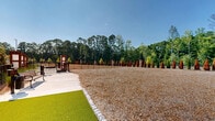 Located at 640 Lakeside Dr in Canton, Georgia, this outdoor dog park is a generously sized, fully enclosed recreational area designed to provide pets with a safe and comfortable space to roam freely. The ground is covered with a thick layer of wood chip mulch, offering a natural, cushioned surface that is easy on paws and helps manage drainage throughout the space.

The perimeter is secured by sturdy black iron fencing, providing clear boundaries while maintaining open sightlines to the surrounding landscape. Elegant wooden gate pillars with decorative lantern-style tops mark the entry and exit points, adding a refined aesthetic touch to the functional design. A row of tall, columnar arborvitae trees lines portions of the interior fence, introducing lush greenery and serving as a natural windbreak.

The park is set against a backdrop of mature, densely wooded trees, giving the space a serene, natural ambiance. On the opposite side, the multi-story residential buildings of the community are clearly visible, reinforcing the park's role as a dedicated amenity within the larger development. The open layout allows for ample room for pets to run and play, while the well-maintained grounds reflect thoughtful upkeep. Under clear blue skies, the space feels bright, airy, and inviting throughout the day.