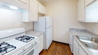 This single-floor unit at 6230 Northview Ln in Toledo, Ohio offers a straightforward, functional layout designed for comfortable everyday living. The entry area features durable hard-surface flooring that transitions into plush carpeting throughout the main living spaces, creating a warm and practical flow between rooms. A ceiling fan is present in the living area, contributing to year-round comfort. The kitchen is efficiently arranged with white cabinetry providing ample storage, granite-patterned countertops, a gas range, a full-size refrigerator, and a dishwasher, all finished in white for a clean, cohesive look. Hard-surface flooring in the kitchen adds durability in this high-use area. The bedroom features soft carpeting and a window offering views of surrounding trees, bringing in natural light and a connection to the outdoors. A second carpeted room features sliding glass doors that open to an enclosed outdoor area, flooding the space with natural light and providing direct exterior access. The full bathroom is well-appointed with white cabinetry, a granite-patterned vanity countertop, a single-basin sink, and a shower-tub combination. Warm-toned wood baseboards throughout the unit add a subtle finishing detail to the overall interior.