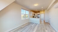 Located at 40 Pleasant St in Barnstable, Massachusetts, this thoughtfully designed single-floor unit offers a clean, contemporary living environment with a cohesive layout and modern finishes throughout. Light gray luxury vinyl plank flooring runs continuously across the entire space, contributing to a bright, cohesive aesthetic.

The open-concept living and kitchen area forms the heart of the unit. Large double-hung windows flood the living space with natural light and provide pleasant views of surrounding greenery. The kitchen is well-appointed with white shaker-style cabinetry, stainless steel appliances including a refrigerator, electric range, and over-the-range microwave, along with a peninsula that defines the cooking area while maintaining an open flow to the living space.

The bedroom is generously sized, benefiting from natural light through its own window, and features two dedicated closets offering ample storage. A wall-mounted mini-split system provides efficient climate control throughout the unit. The bathroom is finished with wood-tone flooring and includes accessibility-friendly grab bar hardware.

The entry area is clean and functional, with a solid white door equipped with a modern lock. The overall palette of soft warm whites and neutral tones creates a calm, inviting ambiance throughout this well-appointed Barnstable residence.