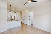 Located at 2825 W 11th St in Houston, TX, this thoughtfully designed one-bedroom, one-bathroom residence offers a clean, modern aesthetic throughout its single-floor layout. Light wood flooring flows seamlessly through every room, complementing the crisp white walls and creating a bright, airy atmosphere.

The open-concept kitchen, dining, and living area serves as the heart of the home. The kitchen is well-appointed with white shaker cabinetry, subway tile backsplash, a large quartz-topped island with an undermount stainless steel sink, sleek pendant lighting with matte black hardware, and a full suite of stainless steel appliances including a French door refrigerator, range, over-the-range microwave, and dishwasher. A ceiling fan overhead adds comfort to the combined living and dining space, which opens to a private balcony through glass French doors framed by transom windows, bringing in generous natural light.

The bedroom is generously proportioned, featuring multiple windows with views to the outdoors, a ceiling fan, and access to two closets for ample storage. A dedicated laundry area adds everyday convenience.

The bathroom is elegantly finished with large-format tile flooring, a glass-enclosed walk-in shower with marble-style tile surround, a white vanity with quartz countertop, and matte black fixtures throughout.