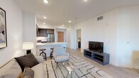 Located on Wilshire Boulevard in the heart of West Los Angeles, this single-floor residence offers a thoughtfully designed open-concept layout with clean lines and contemporary finishes throughout. Light wood-tone flooring runs seamlessly across the living areas, enhancing the bright, airy atmosphere created by recessed lighting and white walls.

The living area is spacious and well-proportioned, providing ample room for a full seating arrangement and dining set, with direct visual connection to the kitchen. The kitchen is a standout feature, outfitted with flat-front cabinetry in a warm woodgrain finish, white quartz countertops, a subway tile backsplash, and a full suite of stainless steel appliances including a gas range, microwave, and refrigerator. A peninsula with bar seating serves as a natural divider between the kitchen and living space.

The bedroom is a calm, well-lit retreat featuring a ceiling fan, a large window with a roller shade, and direct access to a closet. The bathroom is clean and modern, with full white subway tile surrounding a soaking tub and shower combination, paired with light porcelain tile flooring. Every area of this residence reflects a consistent, modern aesthetic well-suited for comfortable urban living in Los Angeles.