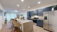 Located at 1599 Oak St in Columbus, Ohio, this thoughtfully designed one-bedroom, one-bathroom residence offers a clean, modern aesthetic throughout its efficiently laid-out single floor. The open-concept kitchen and living area serves as the heart of the home, anchored by a striking kitchen with bold navy-blue cabinetry that extends to the ceiling, providing ample storage. A large quartz-topped island with bar seating and an integrated sink adds both function and style, complemented by a full suite of stainless steel appliances including a refrigerator, range, and microwave. Light wood-tone flooring flows seamlessly throughout, lending warmth and continuity to the space. The living room is bright and inviting, featuring a wall-mounted TV, a glass-panel door that opens to a private outdoor deck, and a wall-mounted mini-split system for climate control. The bedroom is a comfortable retreat with its own mini-split unit, a ceiling fan, and sliding door access with vertical blinds. The bathroom features a floating white vanity, walk-in shower, and clean, contemporary finishes. A hallway and dedicated closet round out the functional layout, making this residence a well-appointed urban home.