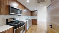 Located at 1525 N Hobart Blvd in the desirable Los Feliz neighborhood of Los Angeles, this thoughtfully designed 3-bedroom, 3-bathroom unit delivers a clean, contemporary aesthetic throughout. Light oak hardwood flooring runs continuously across the main level, complemented by crisp white walls and recessed lighting that create a bright, welcoming atmosphere.

The kitchen is a standout feature, outfitted with rich walnut-toned cabinetry, a marble-style tile backsplash, quartz countertops, and a full suite of stainless steel appliances including a gas range, dishwasher, and over-the-range microwave. It opens seamlessly to the living area, enhancing the sense of openness.

A well-proportioned hallway connects the bedrooms, each finished with the same warm hardwood flooring. The bedrooms feature natural light through sleek, black-framed vertical windows offering neighborhood views, and include mirrored sliding closets for practical storage. Natural wood interior doors with matte black hardware add a refined design touch throughout.

The three bathrooms are elegantly appointed with large-format porcelain tile, glass-enclosed walk-in showers with mosaic tile flooring, built-in niche shelving, and backlit LED mirrors, offering a spa-like experience. The overall design balances modern minimalism with warm material choices for a polished, livable result.