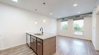 Located at 5401 Chicago Ave in Minneapolis, MN, this one-bedroom, one-bathroom unit offers a well-designed layout that makes efficient use of its space. The open-concept kitchen and living area serves as the heart of the unit, anchored by a large central island with a granite countertop, undermount double sink, and matte black faucet. Dual pendant lights hang above the island, adding a modern touch. The kitchen is equipped with stainless steel appliances — including a refrigerator, electric range, and microwave — complemented by rich dark cabinetry, a white subway tile backsplash, and hardwood-style flooring that flows throughout the main living area. Large windows allow natural light to fill the living space while offering views of surrounding greenery. The bedroom features plush carpeting, a window with outdoor views, and exposed ductwork that adds an industrial character to the space. It connects directly to a spacious walk-in closet outfitted with wire shelving on three walls, providing generous storage. The bathroom includes a full soaking tub and shower combo with crisp white surround and matte black fixtures. The unit's clean, contemporary finishes and functional layout make it a comfortable and practical living space in Minneapolis.