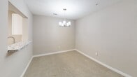 This single-floor residence offers a thoughtfully designed layout with 2 bedrooms, 3 bathrooms, and a range of modern finishes throughout. The kitchen is outfitted with white shaker cabinetry, granite-look countertops, stainless steel appliances including a refrigerator, range, and microwave, and warm wood-look flooring. A dedicated walk-in pantry closet adjacent to the kitchen provides generous storage. The dining room features plush carpeting and is accented by a contemporary chandelier, creating a welcoming space for meals. The primary bedroom is a well-proportioned retreat with carpet flooring and natural light filtering through large windows with outdoor views. Its en-suite bathroom is a standout, featuring a double vanity with granite countertops, white cabinetry, a corner soaking tub, and wood-look flooring. The second bedroom also features carpet flooring and an open closet with a clothing rod. A convenient half bathroom with wood-look flooring serves the common areas. Throughout the residence, neutral warm-toned walls, white trim, and consistent flooring choices create a cohesive and clean aesthetic. A hallway and additional closet space further enhance the home's practical and organized flow.