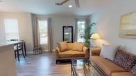 Located at 2889 Sollie Rd in Mobile, Alabama, this single-story home offers a well-organized, comfortable layout with thoughtful finishes throughout. The living area is bright and welcoming, featuring wood-look laminate flooring, neutral-toned walls, and multiple windows that allow natural light to fill the space. Ceiling fans add both functionality and a casual charm to the room.

The kitchen is equipped with stainless steel appliances, including a range, microwave, and refrigerator. Cream-colored cabinetry pairs with granite-style countertops to create a clean, functional workspace. The kitchen flows naturally into a dedicated dining nook, which is framed by large windows and a glass door that brings in additional natural light. An elegant chandelier overhead adds a refined touch to the dining area.

The bedroom offers a serene retreat with plush carpet flooring, large windows with blinds, and a ceiling fan. The room's soft, neutral palette contributes to a calm and restful ambiance.

The bathroom features a clean, white tub-shower combination with modern brushed nickel fixtures and a curved shower rod. Overall, the home presents a cohesive, move-in-ready aesthetic with consistent flooring, neutral color schemes, and practical finishes that balance everyday comfort with understated style.