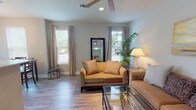 Located at 2889 Sollie Rd in Mobile, Alabama, this single-story home offers a well-organized, comfortable layout with thoughtful finishes throughout. The living area is bright and welcoming, featuring wood-look laminate flooring, neutral-toned walls, and multiple windows that allow natural light to fill the space. Ceiling fans add both functionality and a casual charm to the room.

The kitchen is equipped with stainless steel appliances, including a range, microwave, and refrigerator. Cream-colored cabinetry pairs with granite-style countertops to create a clean, functional workspace. The kitchen flows naturally into a dedicated dining nook, which is framed by large windows and a glass door that brings in additional natural light. An elegant chandelier overhead adds a refined touch to the dining area.

The bedroom offers a serene retreat with plush carpet flooring, large windows with blinds, and a ceiling fan. The room's soft, neutral palette contributes to a calm and restful ambiance.

The bathroom features a clean, white tub-shower combination with modern brushed nickel fixtures and a curved shower rod. Overall, the home presents a cohesive, move-in-ready aesthetic with consistent flooring, neutral color schemes, and practical finishes that balance everyday comfort with understated style.