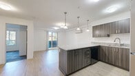 Located at 2699 Peatt Rd in Langford, BC, this well-designed one-bedroom, one-bathroom unit offers a thoughtful layout across a single floor. The open-concept living and kitchen area is a clear highlight, anchored by a substantial island topped with speckled granite countertops and illuminated by a trio of stylish pendant lights. Dark wood-toned cabinetry contrasts beautifully with the light hardwood-style flooring, while stainless steel appliances—including a full-size refrigerator, range, and built-in microwave—complete the modern kitchen. The living area is spacious and bright, featuring a wall-mounted ductless heating and cooling unit for year-round comfort. The bedroom offers a cozy retreat with plush carpet tile flooring and a window that allows natural light to filter in. The bathroom echoes the unit's design language with wood-toned cabinetry and granite countertops. A dedicated in-unit laundry room with side-by-side machines and built-in shelving adds exceptional practicality. Clean white walls, consistent finishes, and light wood flooring throughout give the space a cohesive, contemporary feel.