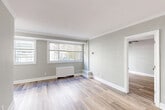Located in the Chevy Chase neighborhood of Washington, DC, this well-appointed one-bedroom, one-bathroom residence offers a thoughtfully designed layout with modern updates throughout. Light-toned, wood-style flooring flows continuously across the living spaces, complemented by soft gray walls and crisp white crown molding that lend the home a clean, contemporary feel.

The open living and dining area is bathed in natural light from large, multi-pane windows that frame views of the surrounding tree-lined streetscape. A radiator unit provides efficient heating, and the generous floor plan allows for flexible furniture arrangements.

The kitchen is efficiently designed with white shaker-style cabinetry, granite countertops, subway tile backsplash, marble-look tile flooring, and stainless steel appliances including a refrigerator and gas range. A dedicated closet area provides additional storage.

The bedroom is a comfortable, well-proportioned retreat featuring a ceiling fan, a wide window with outdoor views, and a mirrored sliding-door closet. The bathroom stands out with a glass-enclosed shower clad in large-format marble-look tiles and sleek brushed nickel hardware, delivering a spa-like aesthetic. Overall, the unit combines classic architectural details with modern, refreshed finishes.