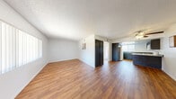 Located at 5001 W El Parque Ave in Las Vegas, NV, this single-floor, 1-bedroom, 2-bathroom residence offers a practical and well-organized layout. The open-concept living and kitchen area is finished with warm wood-style laminate flooring and textured ceilings throughout. Large windows allow natural light to fill the living space, which also features a ceiling fan and direct access to a private outdoor patio via sliding glass doors. The kitchen is equipped with dark cabinetry, granite-style countertops, a peninsula breakfast bar, white appliances including a refrigerator, electric range, microwave, and dishwasher, along with a skylight that brightens the workspace. The bedroom offers plush carpeting, a built-in closet, and convenient access to one of the two full bathrooms. Both bathrooms feature wood-style flooring, granite-style vanity countertops, and a tub/shower combination. A hallway with additional storage connects the main areas of the home. A dedicated closet provides further organizational flexibility. The space is efficiently designed to maximize comfort and functionality throughout.