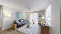 This single-floor residence offers a thoughtfully designed layout that balances comfort and functionality across its key living spaces. The living room serves as the heart of the home, featuring wood-look flooring, a textured ceiling with a ceiling fan, and an abundance of natural light streaming through large windows fitted with blinds. A sliding glass door opens directly onto a private balcony, extending the living space outdoors. Neutral wall tones provide a versatile backdrop throughout.

The kitchen is equipped with stainless steel appliances, including an electric range and an over-the-range microwave, complemented by white shaker-style cabinetry and light gray countertops — a clean, practical setup for everyday cooking.

The bedroom is a relaxing retreat, carpeted for warmth and comfort, with a ceiling fan, a window with blinds for natural light and privacy, and ample space for furnishings.

The bathroom features a full tub-and-shower combination with white tile surround, wood-look flooring, and soft neutral wall tones, creating a clean and calming environment.

Overall, the space presents a cohesive aesthetic with consistent finishes, practical amenities, and a layout that maximizes livability across every room.
