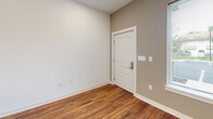 Located at 422 Garrett St in Charlottesville, VA, this two-floor unit offers a clean, modern aesthetic defined by warm hardwood-style flooring and neutral wall tones that flow consistently throughout the space. The open-concept kitchen serves as a central hub, featuring a peninsula with light stone countertops, rich medium-toned wood cabinetry both above and below, and pendant lighting that adds a contemporary touch. The kitchen connects seamlessly to the main living area, which benefits from natural light through large windows fitted with blinds, offering views of the surrounding neighborhood.

Bedrooms are well-proportioned, with multiple rooms featuring generous closet storage, including a spacious walk-in closet outfitted with multi-tiered wire shelving systems. One bedroom provides dual sets of double doors for ample storage, while others include large windows that invite natural light. A dedicated utility area is equipped with an extended run of upper and lower cabinetry with countertop workspace.

The unit includes two full bathrooms, each featuring a tub/shower combination with gray subway tile surround and chrome fixtures. One bathroom includes a wood-toned vanity with a white countertop and a window for added ventilation. Throughout the space, crisp white trim and clean finishes contribute to a bright, well-maintained atmosphere.