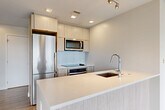 Located at 301 M St SW in Washington, DC, this 2-bedroom, 2-bathroom residence offers a thoughtfully designed single-floor layout with modern finishes throughout. The open-concept living and dining area is bathed in natural light, courtesy of expansive floor-to-ceiling windows that frame sweeping views of the Washington, DC skyline and surrounding neighborhoods. Light-toned hardwood-style flooring runs throughout the main living spaces, enhancing the bright, airy atmosphere.

The contemporary kitchen is a standout feature, equipped with stainless steel appliances including a refrigerator, range, and microwave, complemented by light wood cabinetry, a subway tile backsplash, and a sleek quartz peninsula with an undermount sink—ideal for both meal prep and casual dining.

Both bedrooms are generously proportioned and bright, with large windows offering city views. The primary bedroom includes dedicated closet space. The two bathrooms are finished with light porcelain tile flooring, floating vanities, and clean, minimalist fixtures; the primary bath features a glass-enclosed shower with marble-style tile surround. Additional conveniences include four closets, a dedicated laundry area, and a connecting hallway that maintains a smooth flow throughout the residence.