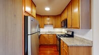 Located at 7520 West Grand Avenue in Elmwood Park, Illinois, this 1-bedroom, 1-bathroom unit offers a thoughtfully designed single-floor layout. Rich, cherry-toned hardwood floors run throughout the entire space, creating a warm and cohesive aesthetic from room to room.

The combined kitchen and living area forms the heart of the unit. The kitchen is well-equipped with warm wood cabinetry extending to the ceiling, granite countertops, a white subway tile backsplash, and stainless steel appliances including a gas range and refrigerator. The open connection to the living area, accented by a ceiling fan, promotes an airy, functional flow.

The bedroom is a comfortably sized retreat featuring large windows that allow natural light to fill the room, along with a sliding mirrored closet that adds both storage and a sense of depth to the space. Baseboard heating and a window AC unit ensure year-round comfort.

The bathroom is finished with neutral ceramic tile flooring, a tiled tub-and-shower surround with an accent border, a vanity with wood cabinetry, and a well-lit, clean layout. Clean white walls and neutral tones throughout the unit create a bright, move-in-ready environment ideal for comfortable everyday living.