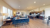 Located at 10913 W Sixth Ave in Airway Heights, WA, this single-story clubhouse offers a generously sized, amenity-rich environment designed for community gathering and recreation. The welcoming entrance hallway features light wood-style flooring, large glass French doors that invite abundant natural light, and tasteful décor that sets an inviting tone throughout.

The open-concept lounge and kitchen area is the heart of the clubhouse. The lounge is furnished with comfortable seating, wall-mounted televisions, and ample natural light streaming through large windows. The adjacent full kitchen is outfitted with rich dark wood cabinetry, granite countertops, a large center island, and black appliances — ideal for community events and gatherings. Mini-split climate control units ensure year-round comfort throughout.

The game room is a standout feature, housing an impressive indoor golf simulator with a large projection screen, a synthetic turf hitting mat, and additional seating for spectators. A projector-equipped flex space nearby provides versatile options for presentations or casual lounging.

The fitness center is bright and well-appointed, featuring rubber flooring, cardio equipment including a stationary bike and treadmill, strength training machines, and a dramatic glass garage door that floods the space with natural light and outdoor views. Together, these spaces create a well-rounded, functional clubhouse experience.