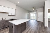 Located in Clear Lake, Iowa, this well-designed 2-bedroom, 1-bathroom residence offers a thoughtful layout across a single floor. The open-concept kitchen and living area serves as the heart of the home, featuring wood-look flooring, recessed lighting, and a ceiling fan. The kitchen is outfitted with stainless steel appliances — including a refrigerator, range, and microwave — two-tone cabinetry with white upper cabinets and dark lower cabinets, light countertops, and a central island that provides additional workspace and casual dining. A sliding glass door leads to a private balcony, filling the living area with natural light. Both bedrooms are carpeted and offer generous closets with built-in shelving. Large windows frame peaceful views of the surrounding Iowa landscape, lending each room a bright, airy feel. The bathroom includes a dark wood vanity with ample storage, a white countertop, and a tub/shower combination with hardwood-style flooring. A dedicated laundry room with a full-size washer and dryer and overhead wire shelving adds everyday convenience. This residence combines modern finishes with a functional floor plan suited for comfortable living.