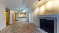This single-floor residence offers a well-organized layout that balances comfort and functionality throughout. The living room serves as the heart of the home, featuring vaulted ceilings, soft carpet flooring, and a classic fireplace framed by a white mantel. Track lighting and a ceiling fan add both style and practicality, while a large window invites natural light and views of the surrounding greenery. A baseboard heating system ensures year-round comfort.

The kitchen is efficiently designed with warm oak cabinetry, gray laminate countertops, and tile flooring. It is equipped with a white refrigerator, electric range, and dishwasher, and opens to the living area via a convenient pass-through breakfast bar. A skylight-style overhead fixture brightens the workspace.

The bedrooms are generously sized, each finished with plush carpet, neutral walls, and ample natural light from individual windows. Baseboard heaters are present in the bedrooms as well.

The bathroom features earthy slate-style tile flooring, a white vanity, and a full tub-shower combination. A hallway connects the main living areas to the private spaces, completing this practical and comfortable single-level layout.