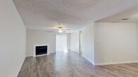 This single-story, 2-bedroom, 1-bathroom home offers a practical and comfortable layout across a compact but efficient floor plan. The living room serves as the heart of the space, featuring durable wood-look plank flooring, a ceiling fan with light fixture, a textured ceiling, and a fireplace that adds warmth and character. A sliding glass door dressed with vertical blinds fills the room with natural light. The kitchen is designed for efficiency, boasting white cabinetry, a pass-through breakfast bar, light countertops, and black appliances including a refrigerator, range, and dishwasher. Both bedrooms are carpeted for comfort and include ceiling fans. The primary bedroom provides access to a dedicated walk-in closet equipped with built-in shelving and hanging rods, as well as a hallway leading directly to the full bathroom. The bathroom features a full tub-shower combination with clean white tile surround. Throughout the home, a neutral color palette of whites and soft grays creates a bright, cohesive aesthetic that makes the space feel open and move-in ready.