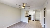 Located at 5150 W Eugie Ave in Glendale, Arizona, this efficient one-bedroom, one-bathroom unit offers a thoughtfully designed layout across a single floor. Light wood-style flooring flows throughout the entire space, complemented by neutral-toned walls and crisp white baseboards that create a clean, modern aesthetic.

The combined kitchen and living area forms the heart of the unit. The kitchen features two-tone cabinetry — white upper cabinets paired with gray lower cabinets — topped with white countertops and equipped with stainless steel appliances, including a full-size refrigerator, electric range, dishwasher, and microwave. A peninsula counter provides additional prep space and serves as a natural divider between the kitchen and living area. An open built-in shelving unit adjacent to the kitchen offers convenient storage. A ceiling fan with an integrated light fixture keeps the living area comfortable.

The bedroom is a well-proportioned, private retreat featuring its own ceiling fan, light-filtering vertical blinds on the window, and the same consistent flooring found throughout the unit. A dedicated closet provides organized storage space.

The bathroom is clean and functional, finished with matching flooring, a dark-cabineted vanity with a white sink, and a full shower/tub combo with bright white surround walls and brushed nickel fixtures.